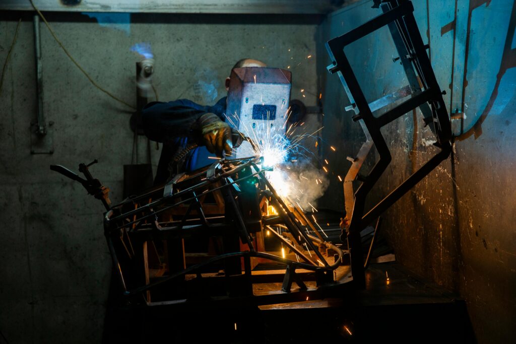 A welder working with sparks and smoke indoors, showcasing industrial skill and safety.